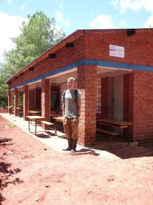 Ich vor der Schule samt Schild der deutschen Botschaft